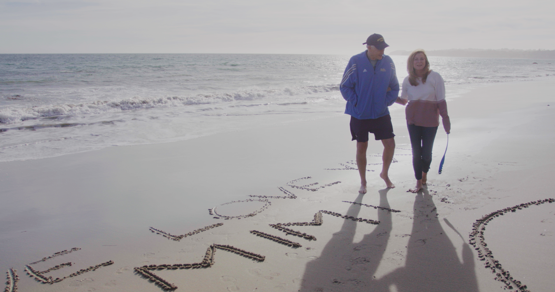 A man and a woman walk on a beach