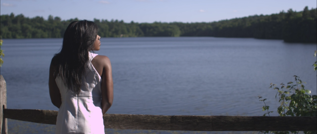 Woman stands looking out at a lake